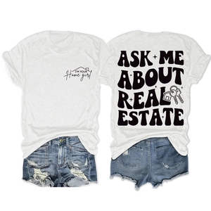 Détail de l'imprimé 'ASK ME ABOUT REAL ESTATE' au dos d'un t-shirt blanc en coton