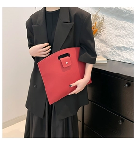 Close-up of red lychee textured leather tote bag with unique cutout handle detail