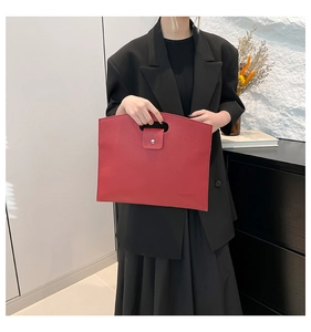Detail of red leather document tote with handle cutout and metal snap closure