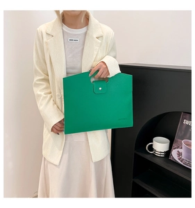 Detail of bright green lychee textured handbag held by model in minimalist white suit