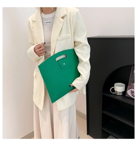 Close-up of green lychee leather envelope clutch with cutout handle and metal snap button