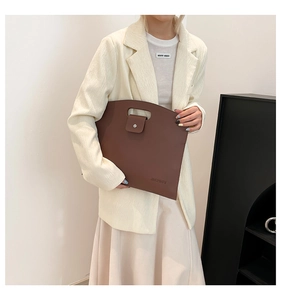 Detail of brown litchi pattern leather laptop bag with handle and metal buckle closure