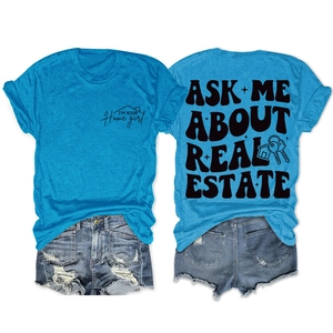 T-shirt bleu avec slogan immobilier et short en jean vieilli posés à plat sur fond blanc