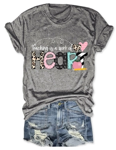 Detail of grey T-shirt with Teaching is a work of Heart print and denim shorts