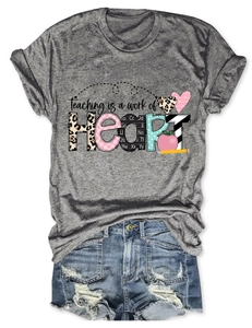 Flat lay of gray T-shirt with 'Teaching is a work of Heart' print and denim shorts