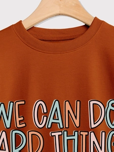 Détail du col côtelé et imprimé 'WE CAN DO HARD THINGS' sur sweat-shirt couleur caramel