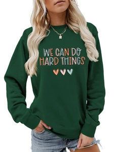 Détail du slogan 'WE CAN DO HARD THINGS' et motif cœur sur le sweat-shirt vert foncé