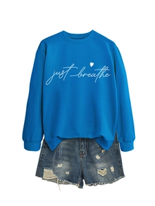Detail of blue crewneck sweatshirt with just breathe text and distressed denim shorts