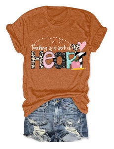 Detail view of orange t-shirt featuring Teaching is a work of Heart print and denim shorts