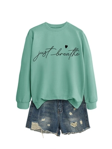 Detail of mint green sweatshirt with 'just breathe' heart print and denim shorts