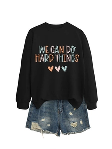 Détail du sweat noir imprimé 'WE CAN DO HARD THINGS' avec un short en jean délavé