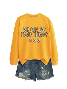 Détail du sweat-shirt jaune imprimé We Can Do Hard Things et short en jean usé