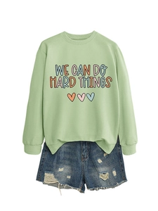 Détail du sweat vert clair avec texte et short en jean assorti au style décontracté