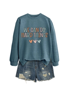 Détail du sweat à col rond bleu avec le slogan We Can Do Hard Things et des cœurs