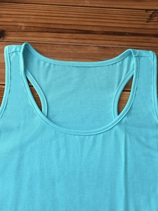 Detailed close-up of the scoop neckline and shoulder strap seams of a cyan cotton tank top
