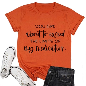 Flat lay of orange crew neck T-shirt with black slogan and denim shorts outfit