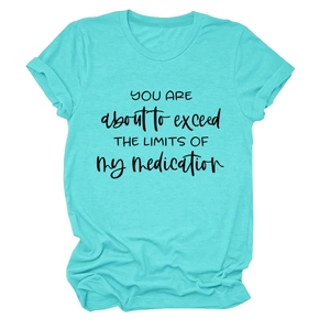 Detail of teal crewneck t-shirt featuring black humorous slogan print on flat lay background