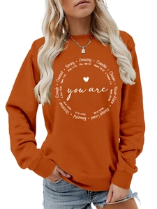 Detail des inspirierenden kreisförmigen Textdrucks auf dem orangefarbenen Sweatshirt