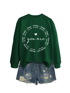 Nahaufnahme des dunkelgrünen Sweatshirts mit 'Created Strong' Text und Denim-Shorts