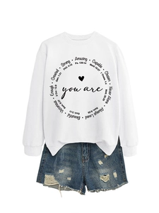 Detail eines inspirierenden weißen Sweatshirts mit Rundtext und distressed Denim-Shorts