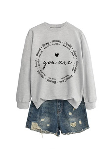 Details von grauem Sweatshirt mit inspirierenden Zitaten und zerrissenen Denim-Shorts