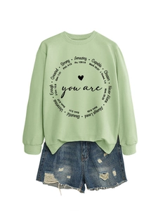 Detail von mintgrünem Sweatshirt mit rundem Schriftzug und Distressed-Denim-Shorts