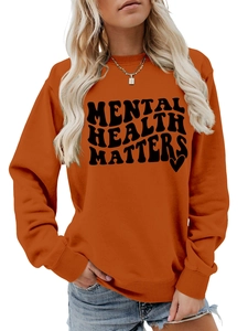 Detail of soft orange crewneck sweatshirt featuring Mental Health Matters text and heart