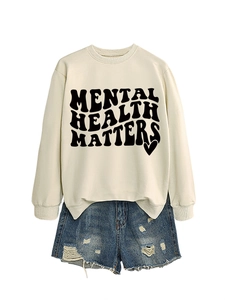 Detail of Mental Health Matters lettering on cream sweatshirt with distressed denim shorts