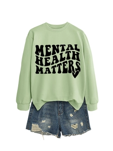Detail view of mint green sweatshirt with Mental Health Matters text and ripped denim shorts