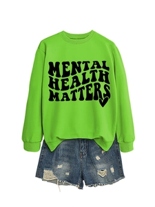 Flat lay of green Mental Health Matters sweatshirt with distressed denim shorts