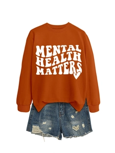 Flat lay of an orange Mental Health Matters sweatshirt with distressed denim shorts