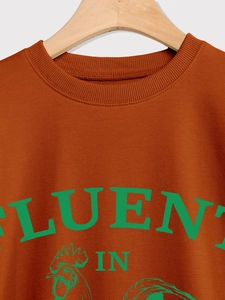 Détail du col côtelé et du graphique de coq vert sur ce sweat-shirt de couleur rouille