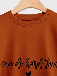 Détail du sweat à col rond caramel avec imprimé texte et cœur sur tissu en coton