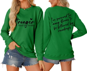 Green sweatshirt detail showing Stronger Than The Storm print and heart graphics
