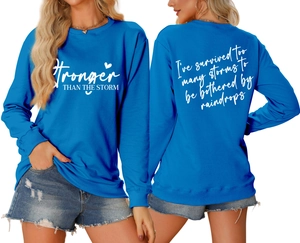 Front and back view of blue sweatshirt showing Stronger Than The Storm print details