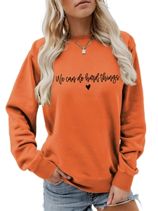 Détail du sweat-shirt orange à col rond avec l'imprimé coeur 'We can do hard things'