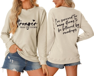 Detail showing the Stronger Than The Storm quote print on casual long sleeve sweatshirt