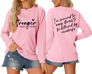 Detail of pink crewneck sweatshirt with 'Stronger THAN THE STORM' print and rib-knit cuffs