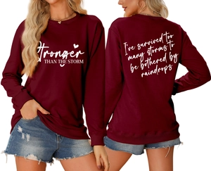 Front and back view of burgundy sweatshirt with white 'Stronger THAN THE STORM' text print
