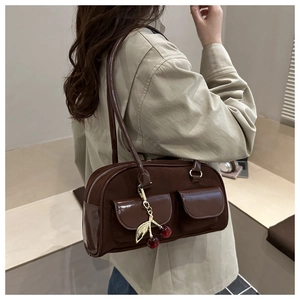 Detail of dark brown retro shoulder bag featuring suede patchwork and cherry charm