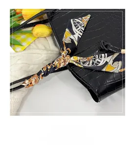 Detail of crocodile pattern texture on black tote bag with silk scarf on handle