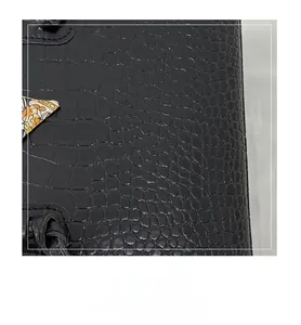 Close-up of black crocodile embossed leather texture with elegant decorative silk scarf