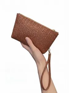 Macro detail of the brown woven leather pattern and wrist strap on this men's clutch