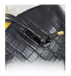 Detail of black crocodile embossed leather tote with golden metallic hardware and stitching