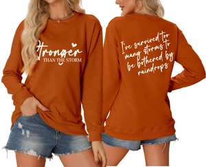 Detailed front and back view of burnt orange sweatshirt with Stronger Than The Storm print