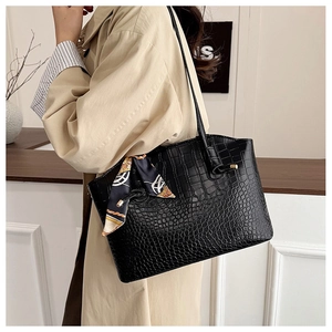Detail of black crocodile texture tote bag with a decorative patterned silk scarf handle