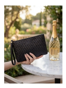 Detail of black woven leather clutch bag with gold zipper and leather wrist strap