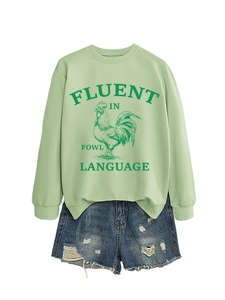 Tenue à plat d'un sweat vert clair avec motif coq et short en jean usé assorti