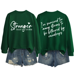 Detail of green Stronger Than The Storm sweatshirt paired with distressed denim shorts