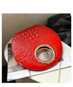Detail of red crocodile texture bag with gold circular handle and chain strap on magazine